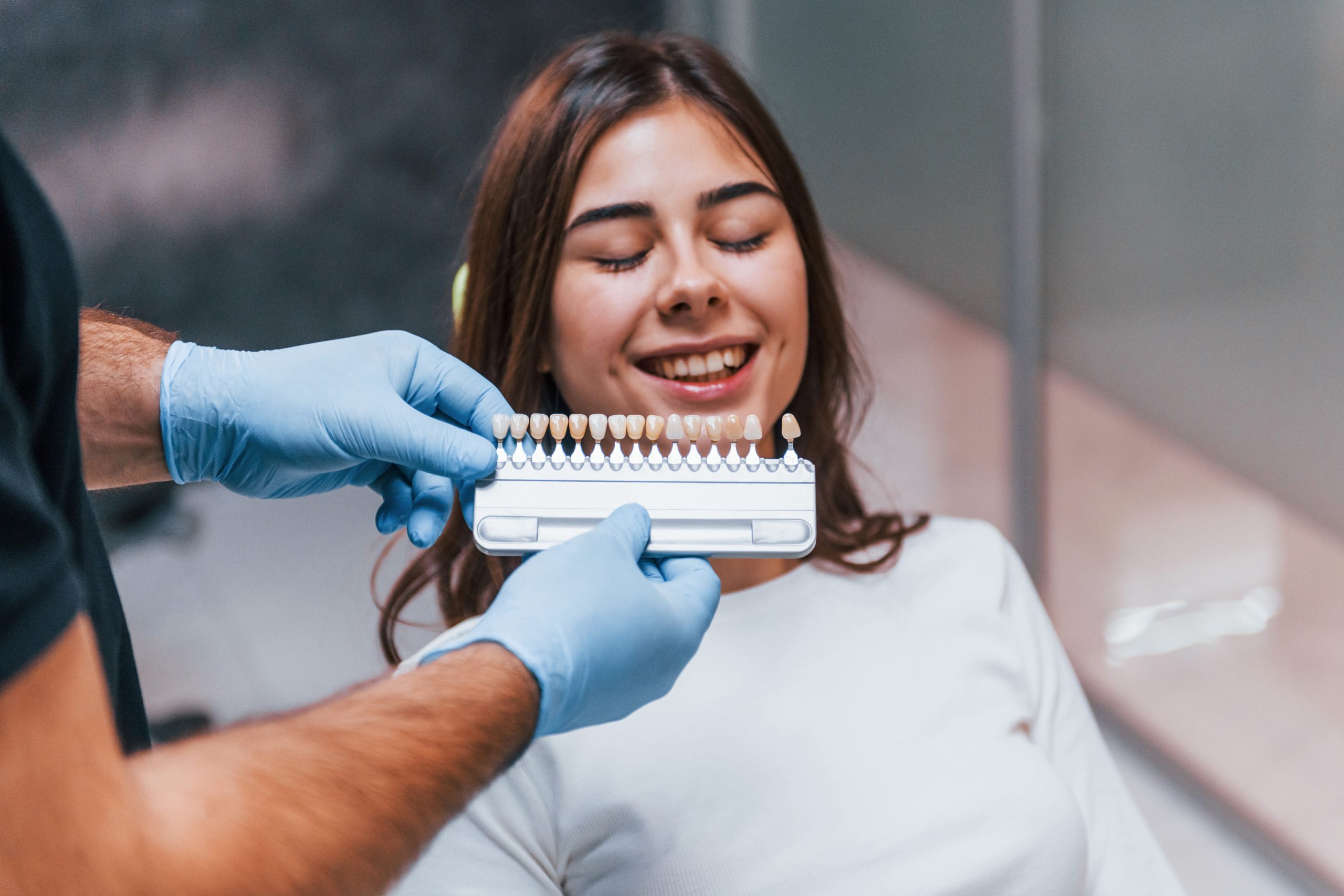 Dentist checking teeth whitening shade with color guide at Reston Serenity Smiles in Reston, VA